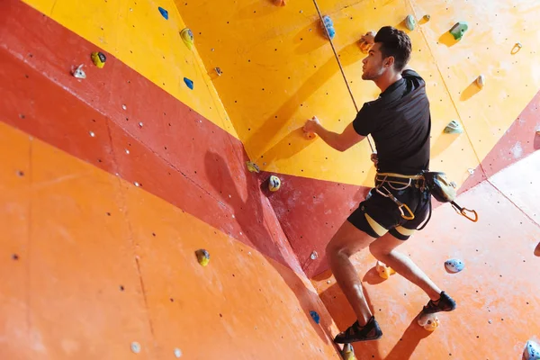 Schöner Mann trainiert hart in Kletterhalle — Stockfoto