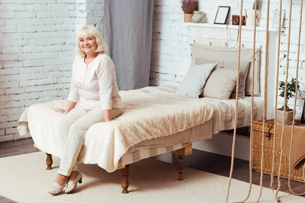 Alegre anciana sentada en la cama — Foto de Stock
