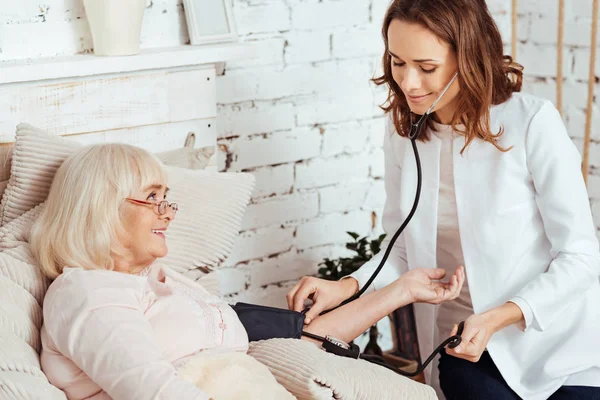 Enfermera encantada midiendo la presión arterial — Foto de Stock