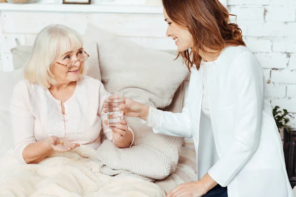 Enfermeira positiva visitando mulher doente em casa — Fotografia de Stock