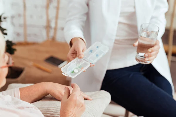 Приятная заботливая медсестра дает таблетки пожилой женщине — стоковое фото