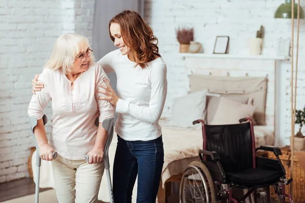 Angenehme fürsorgliche Frau hilft bei der Rehabilitation ihrer behinderten Großmutter — Stockfoto