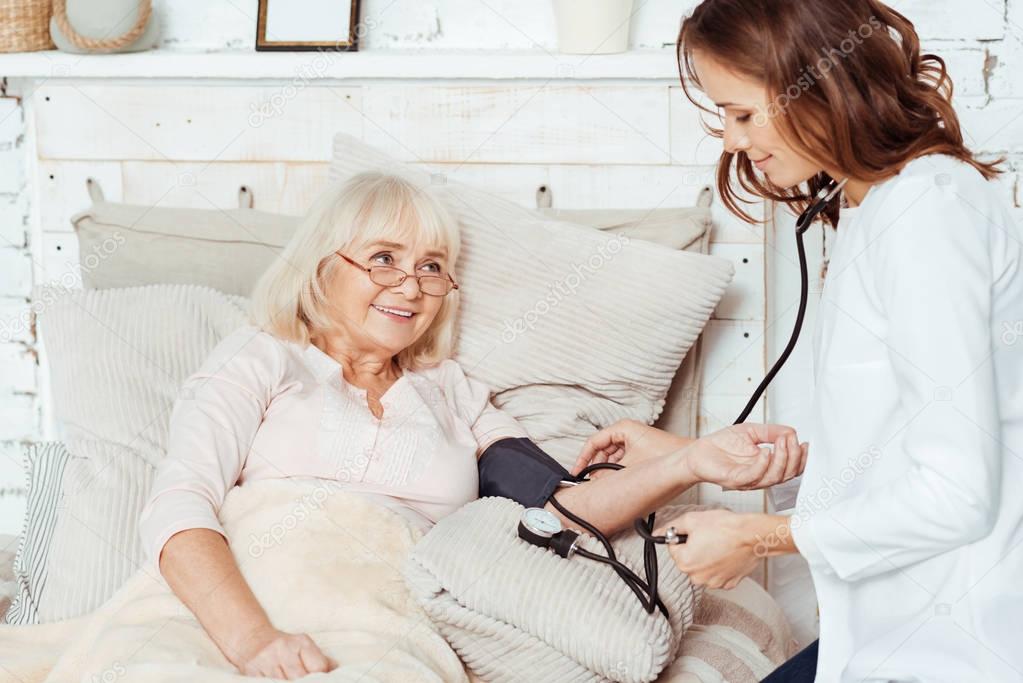 Pleasant nurse measuring blood presure of her patient