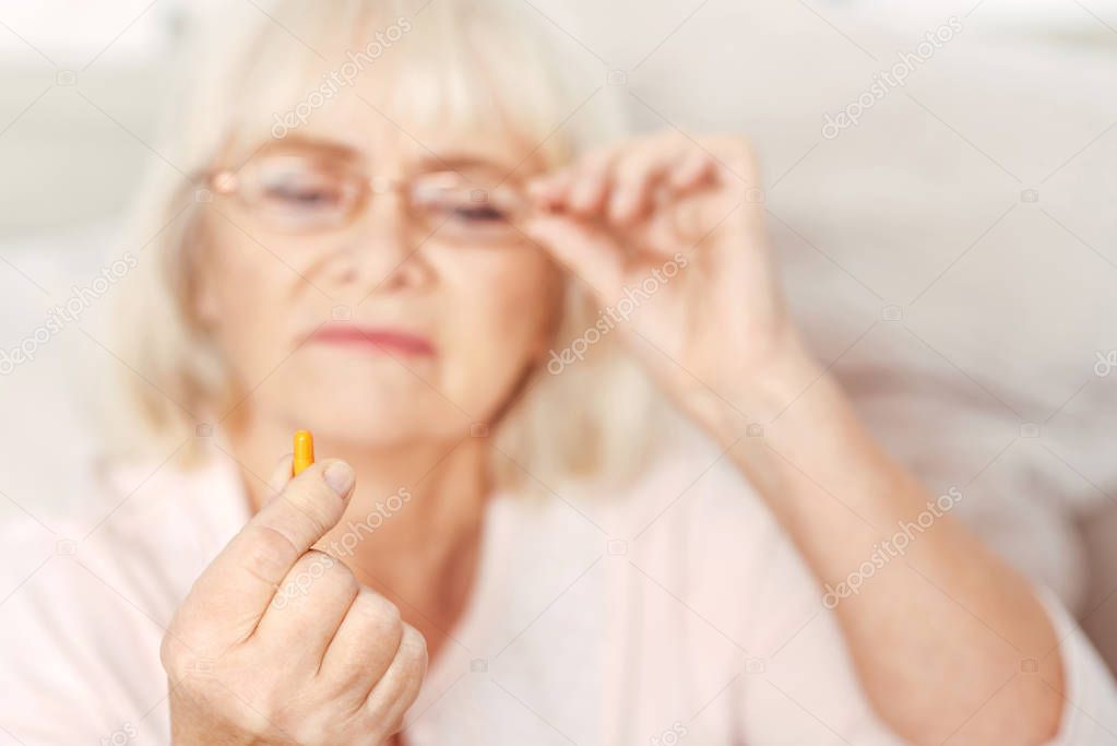 Sick aged woman holding pill