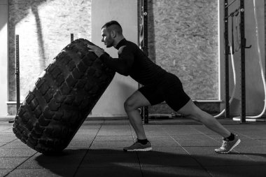 Büyük bir lastik tutan güçlü yakışıklı vücut geliştirmeci