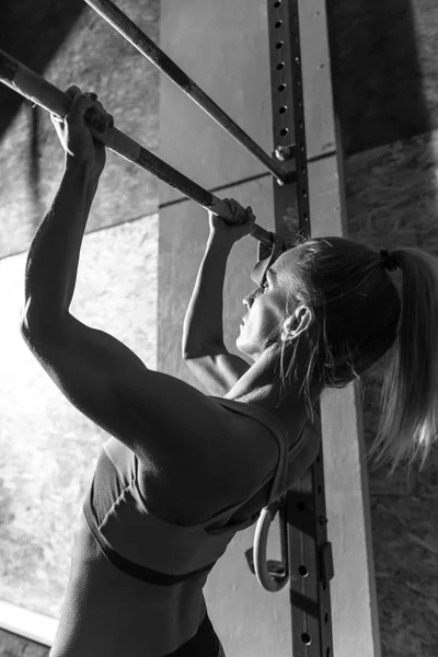 Mujer atlética bien construida haciendo flexiones de barbilla —  Fotos de Stock