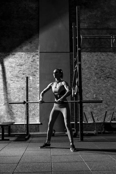 Joven mujer delgada haciendo ejercicio con una larga barra de metal — Foto de Stock