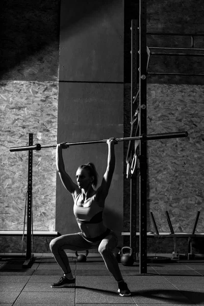 Спортивная спортсменка, сидящая на корточках с длинным металлическим прутом — стоковое фото