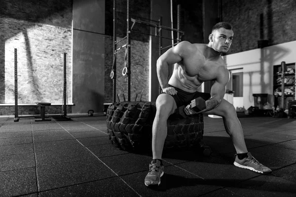 Homem atlético forte se exercitando em um pneu gigante — Fotografia de Stock