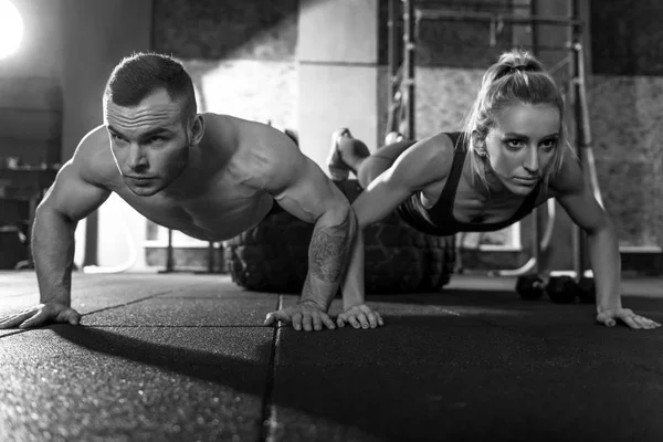 Silne lekkoatletycznego mężczyzna i kobieta robi push upy — Zdjęcie stockowe