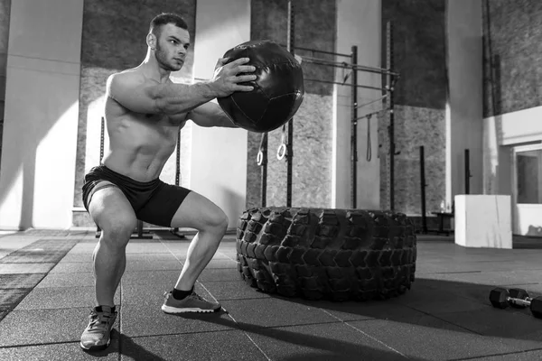 Musculoso buen hombre haciendo ejercicio con una pelota de medicina —  Fotos de Stock