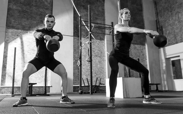 Treningu lekkoatletycznego partnerów gospodarstwa kettlebells przed nimi — Zdjęcie stockowe