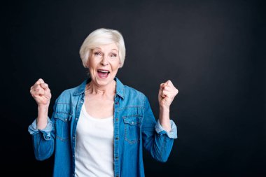 Siyah arka plan üzerinde duran memnun yaşlı kadın