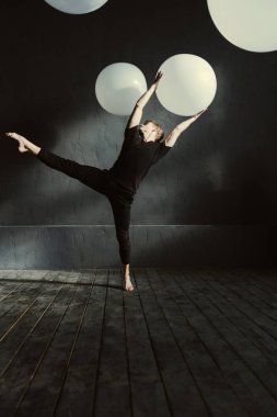 Yetenekli dansçı karanlık duvarın önünde gerçekleştirme