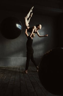 Ustaca jimnastikçiler birlikte siyah renkli stüdyoda dans