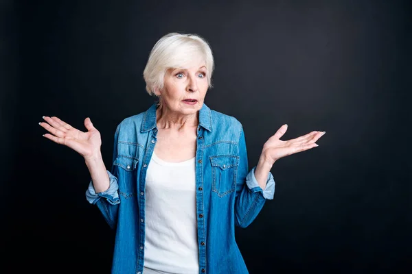 Mujer anciana confusa de pie sobre fondo negro — Foto de Stock