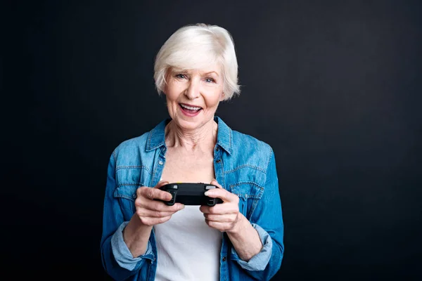 Cheerful elderly woman holdign game console