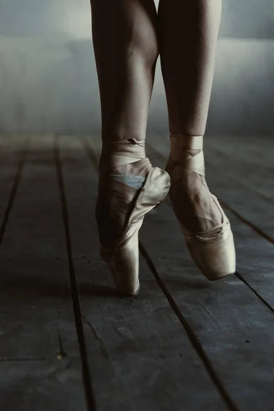 Balletdanseres staand op de tenen op de zwarte kamer — Stockfoto