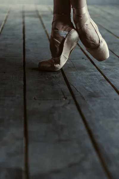 Dançarina de balé alongando-se em dedos do pé na sala preta — Fotografia de Stock