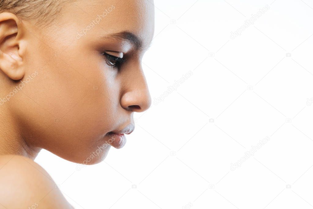 Concentrated young Negroid woman expressing tenderness in the studio
