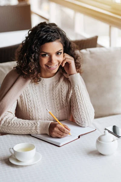 Alegre mujer afroamericana tomando notas en el café — Foto de Stock