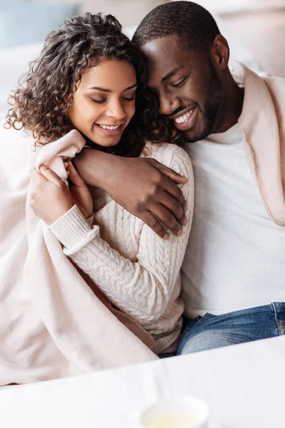 Blij jonge Afrikaanse Amerikaanse echtpaar zitten en knuffelen — Stockfoto