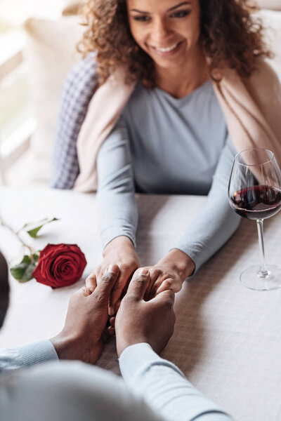 Забавная афроамериканская пара, держащаяся за руки в ресторане
