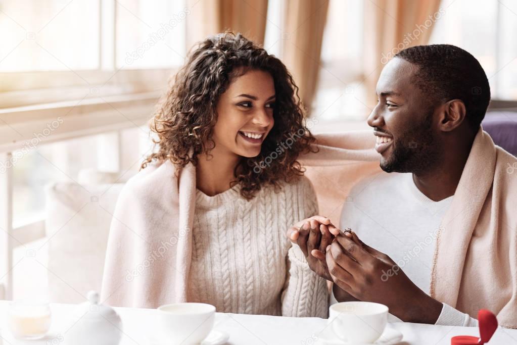 Delighted African American couple getting engaged in the cafe