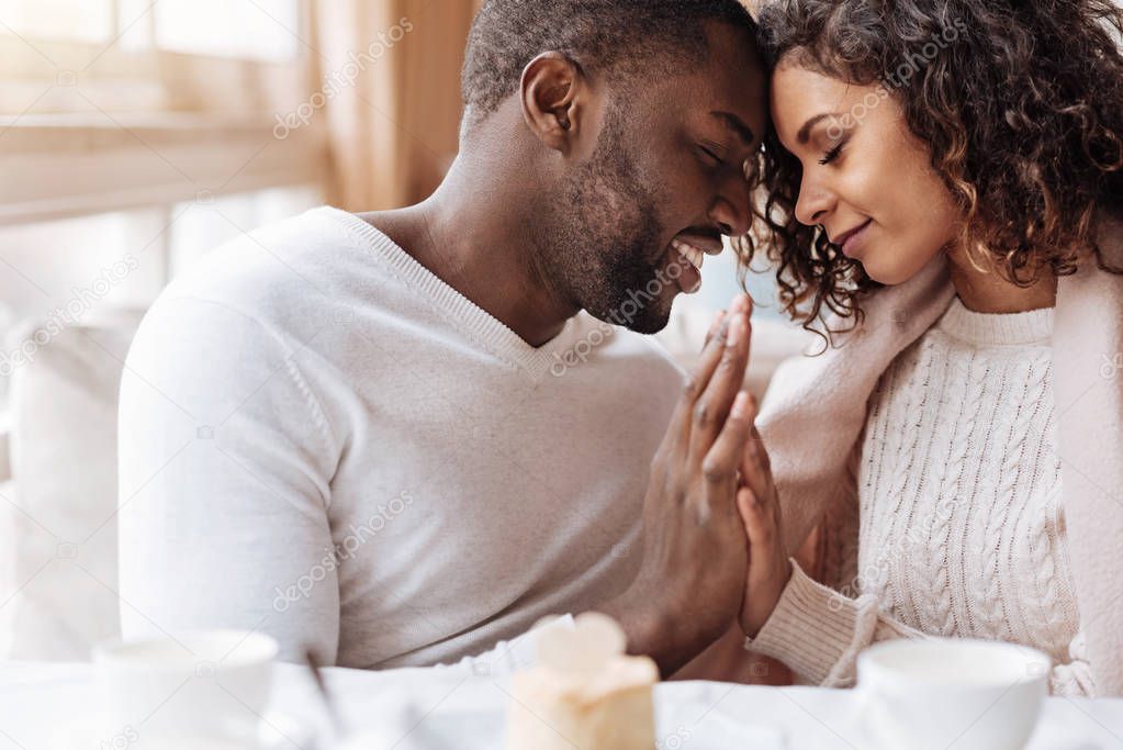 Passionate African American couple touching hands in the cafe