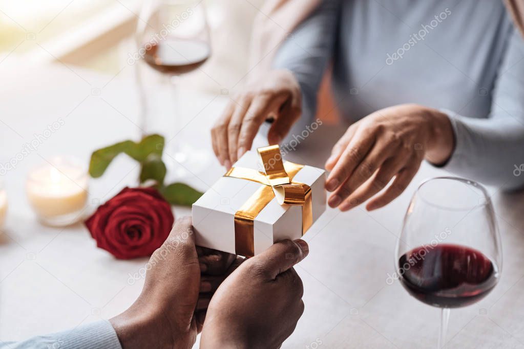 Happy African American woman opening the box from her boyfriend