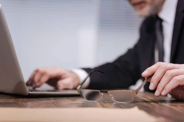 Elegante caballero sosteniendo sus gafas — Foto de Stock