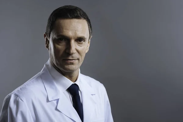 Portret lekarza stojąc na szarym tle — Zdjęcie stockowe