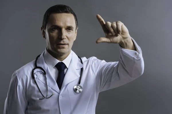 集中的医生做手势在灰色的背景上 — 图库照片