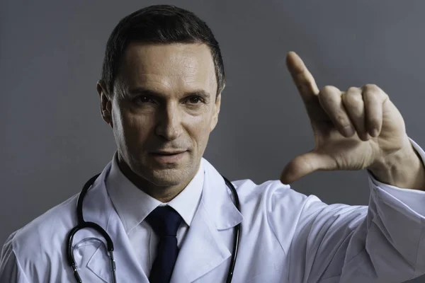 Portrait of concentrated doctor gesturing on a grey background — Stock Photo, Image