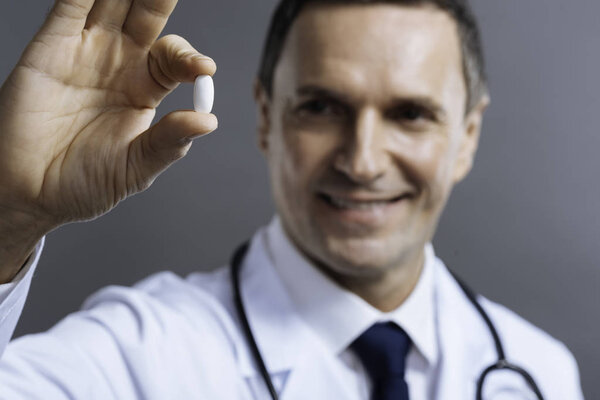 Крупным планом радостного доктора, держащего таблетку
