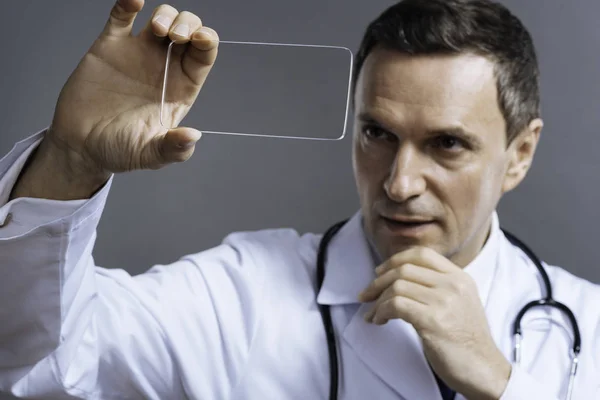 Concentrated doctor looking through glass — Stock Photo, Image