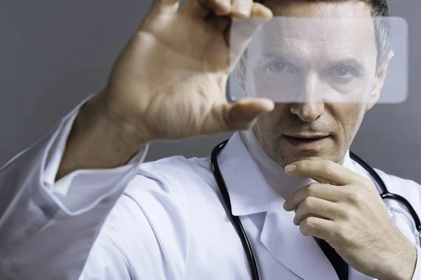 Skoncentrowane lekarz odkrywanie czegoś przez specjalne szkło — Zdjęcie stockowe