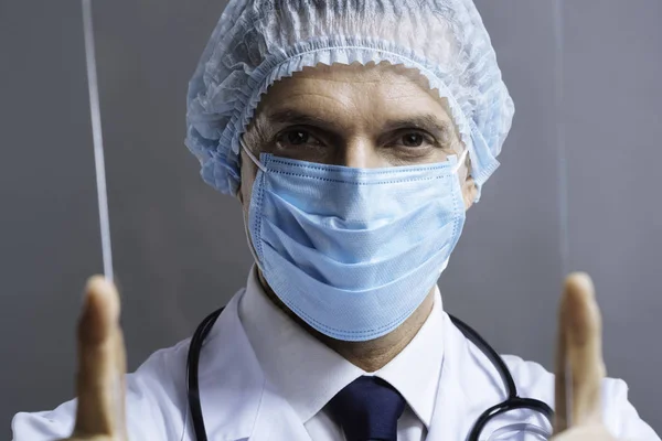 Retrato de un médico inteligente mirando a través del vidrio médico — Foto de Stock