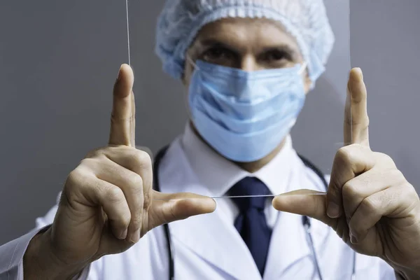 Close up of attractive doctor looking through medical glass — Stock Photo, Image