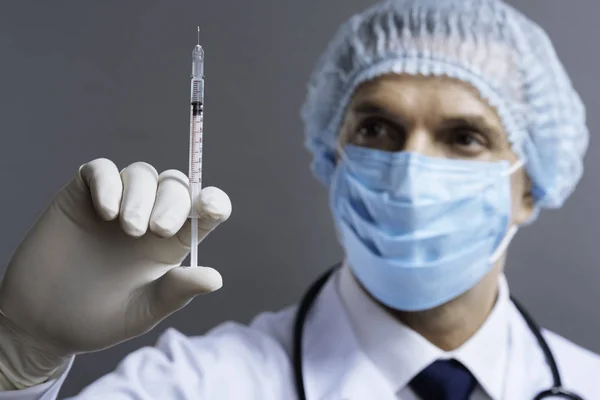 Handsome doctor holding hypodermic needle — Stock Photo, Image