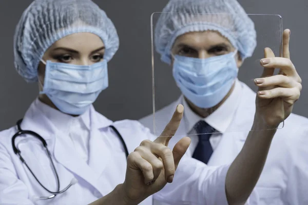 Konzentrierte Kollegen berühren medizinisches Glas — Stockfoto