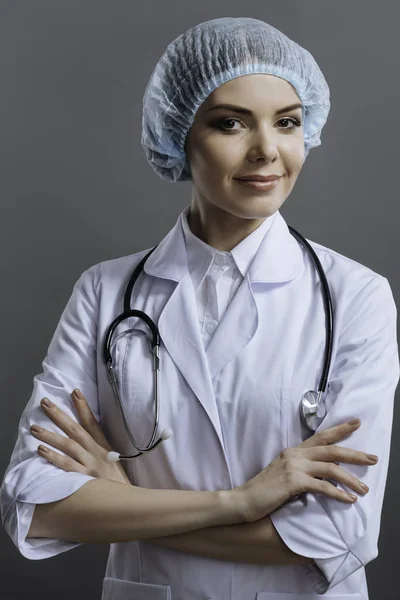 Attraktiva läkare stående på en grå bakgrund — Stockfoto