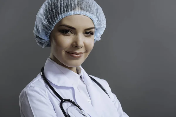Médica sorrindo em um fundo cinza — Fotografia de Stock