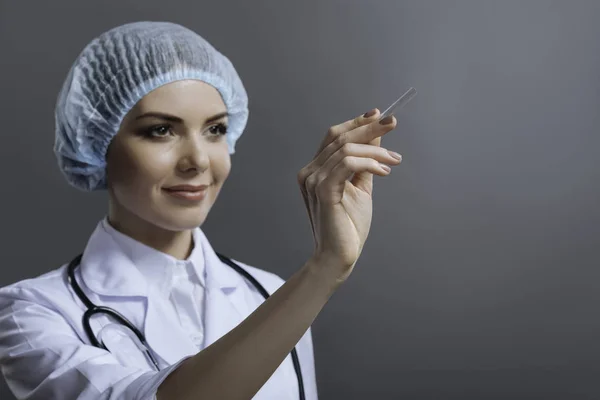 Ärztin demonstriert Spachtel auf grauem Hintergrund — Stockfoto