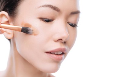 Nice asian woman applying several layers of liquid foundation