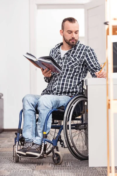 Koncentruje się niepełnosprawny mężczyzna spisywać coś — Zdjęcie stockowe