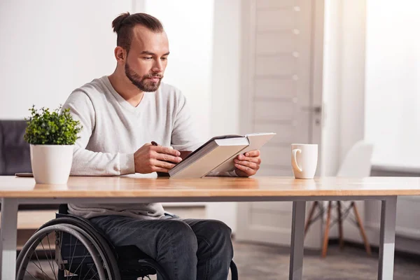 Smart disabled guy reading during breakfast