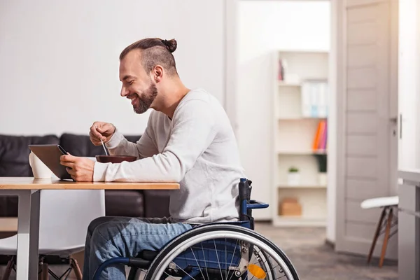 Smiling disabled guy reading emails during breakfast — Stock Photo, Image