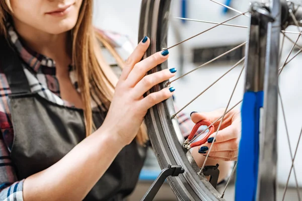 Inblandade kvinna reparera cykeln i garaget — Stockfoto