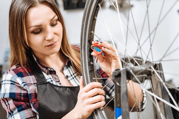 Geconcentreerde jonge vrouw repareren de fiets in de garage — Stockfoto